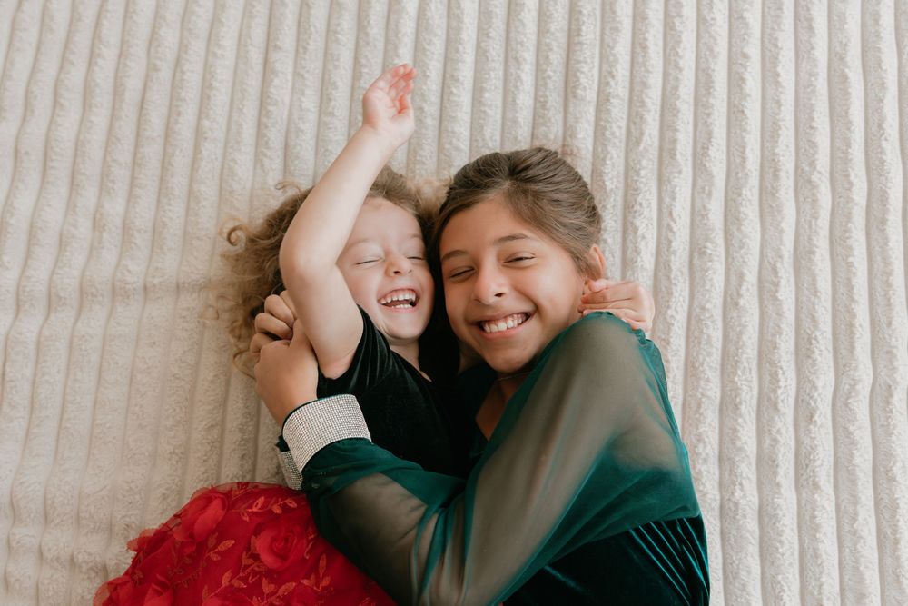 People lying on white bedding share joyful laughter together in a candid moment.