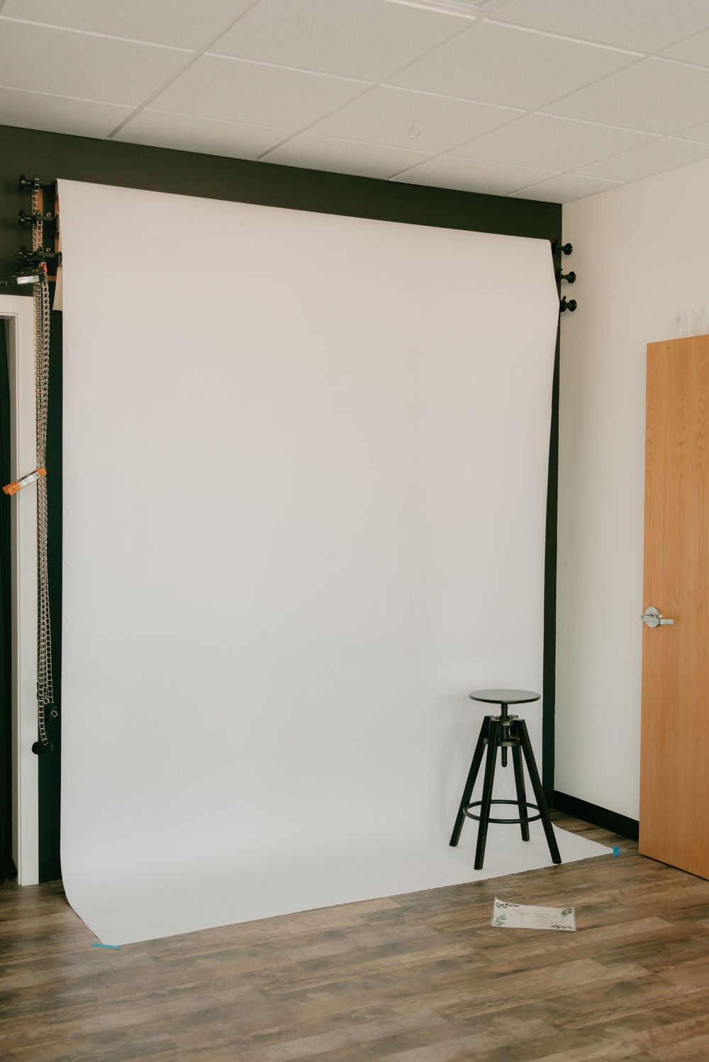 Professional photography studio with white backdrop and wooden flooring in a clean, modern space.