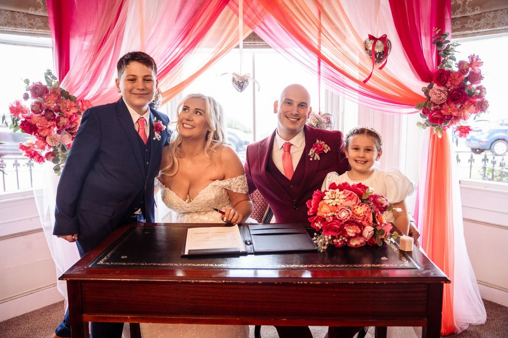 A wedding ceremony setup with pink draping and floral decorations in an elegant indoor venue.