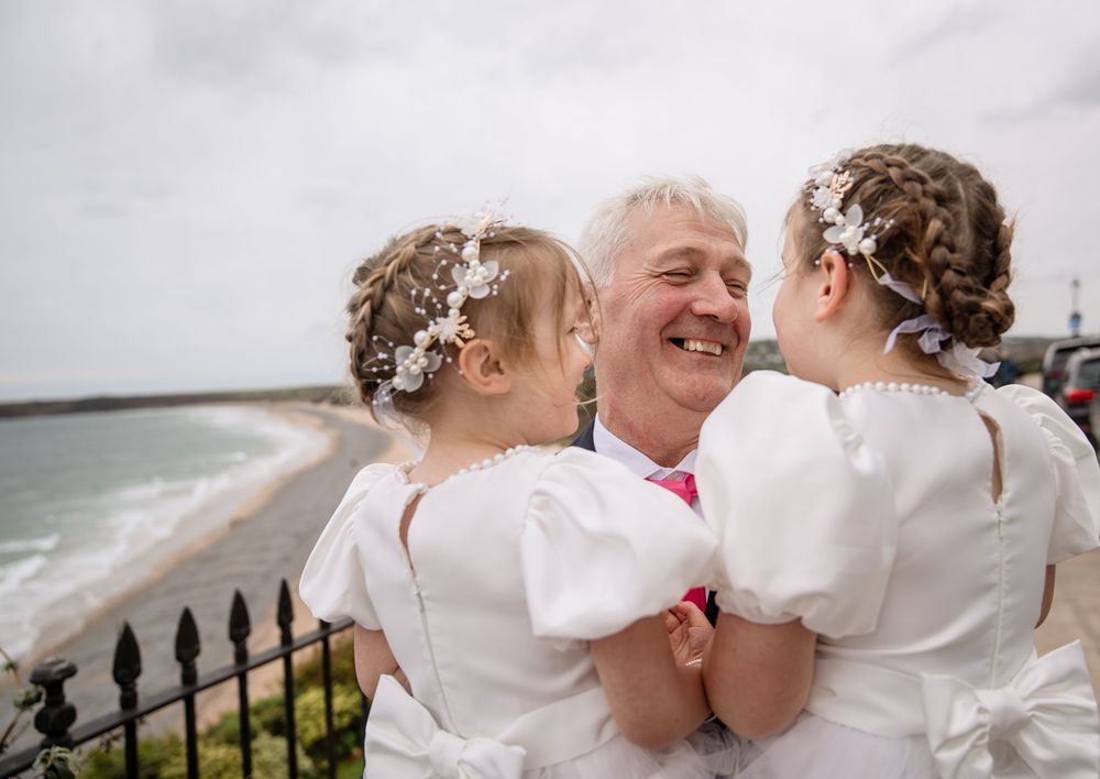 Romantic couple in white wedding attire sharing intimate moments by the ocean during their wedding day celebration.