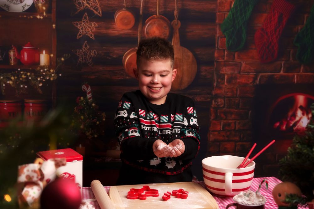 A festive holiday table setting with red decorations, candy canes, and hot cocoa with marshmallows against a brick wall backdrop.