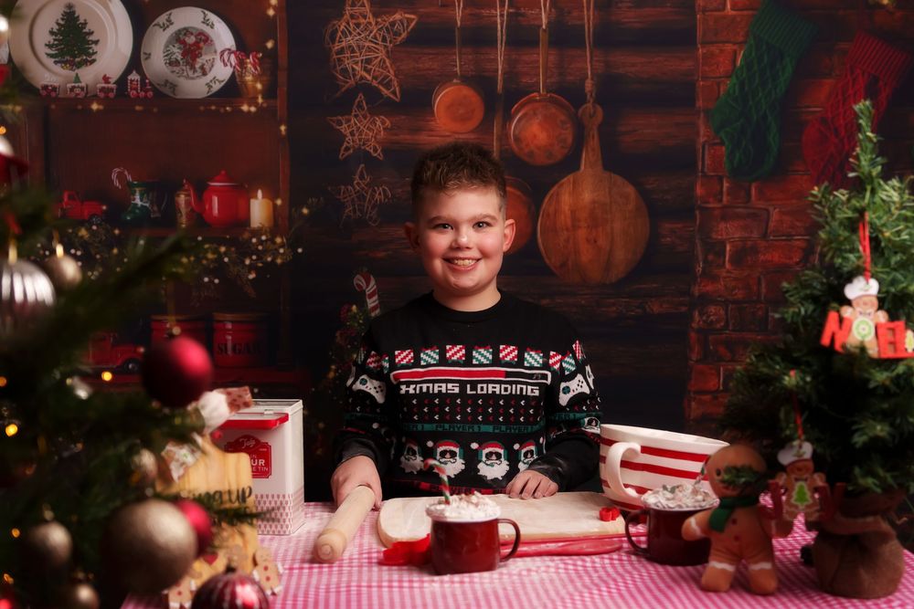 Christmas themed table setting with red checkered tablecloth, wine glasses, and festive decorations in warm lighting.