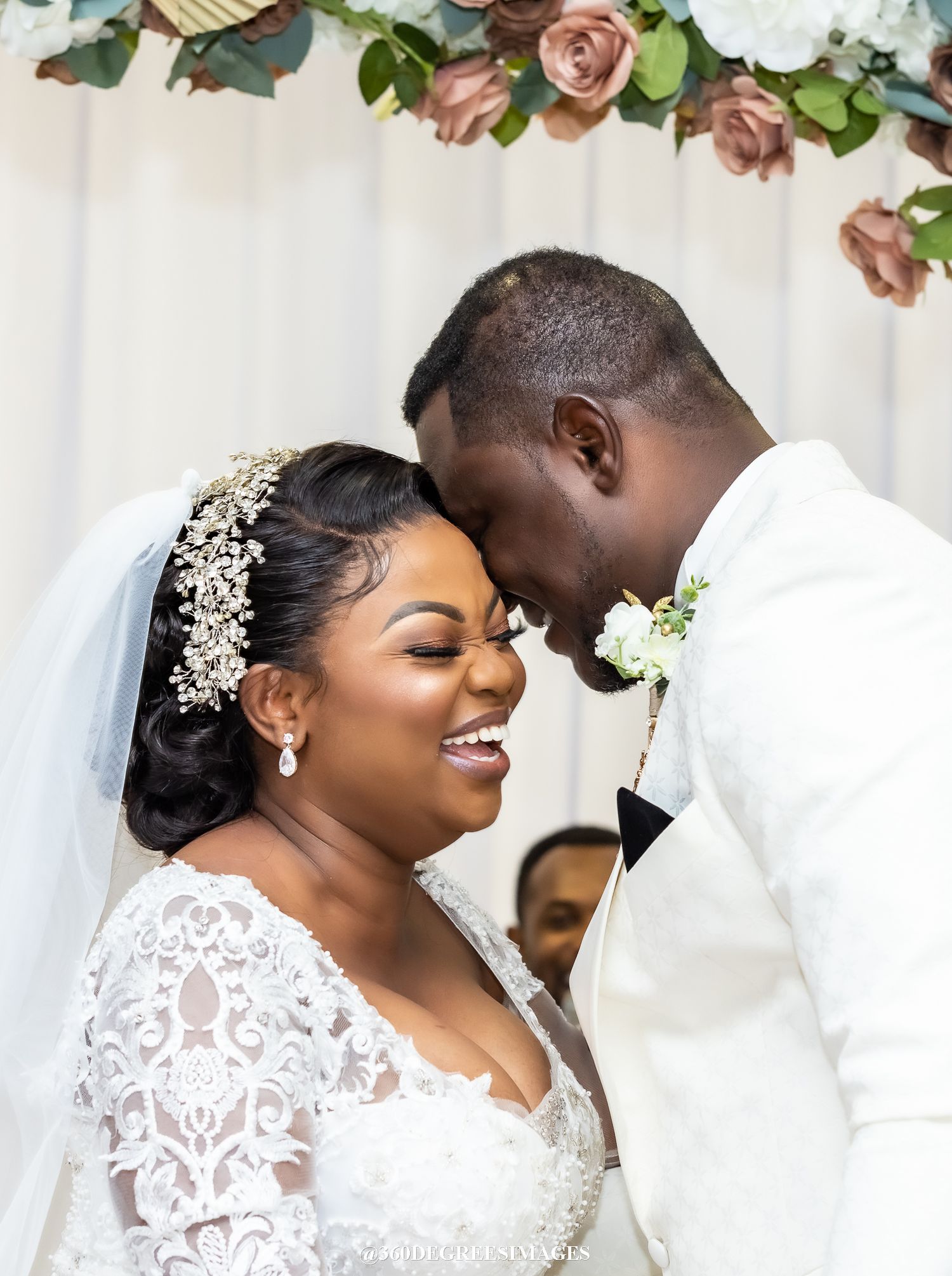 A joyful wedding celebration with a couple in elegant white attire and floral decorations in the background.