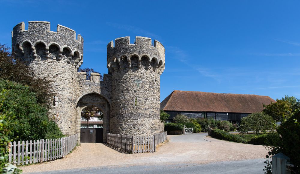 Medieval stone gatehouse with twin turrets and crenellated towers stands at entrance to historic Cooling Castle in Kent.