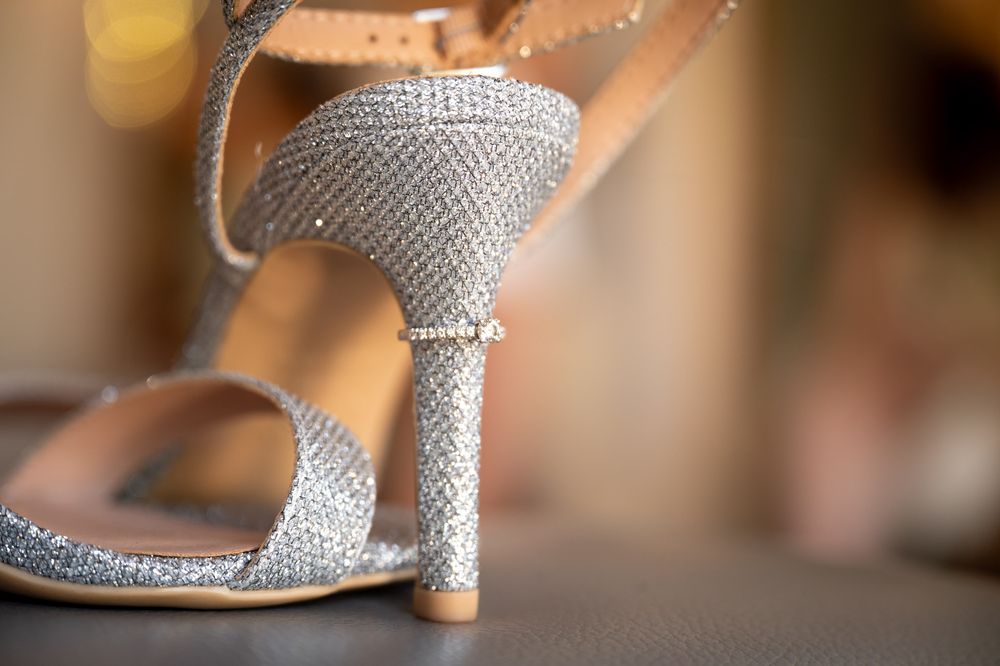 Close-up of sparkly silver kitten heel sandals with rhinestone details displayed at a wedding at Cooling Castle Barns in Kent.