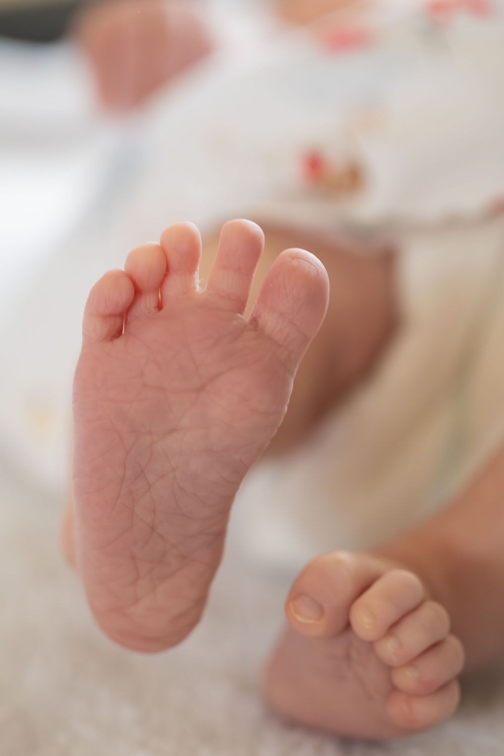 Close-up view of tiny newborn baby feet showing delicate pink skin and natural creases on the soles.