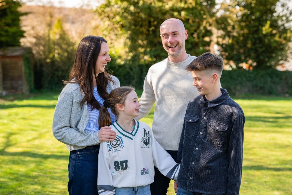 A group enjoys a candid conversation while standing together in a sunny park on an autumn afternoon.