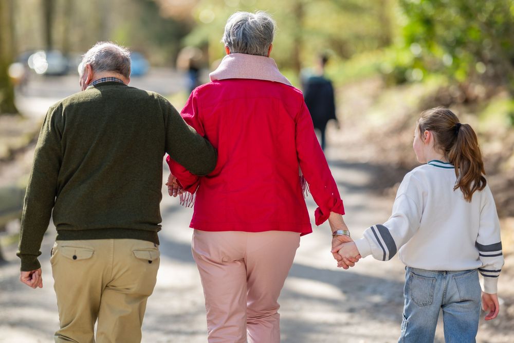 A group of people walking together on a path through a park on a sunny autumn day.