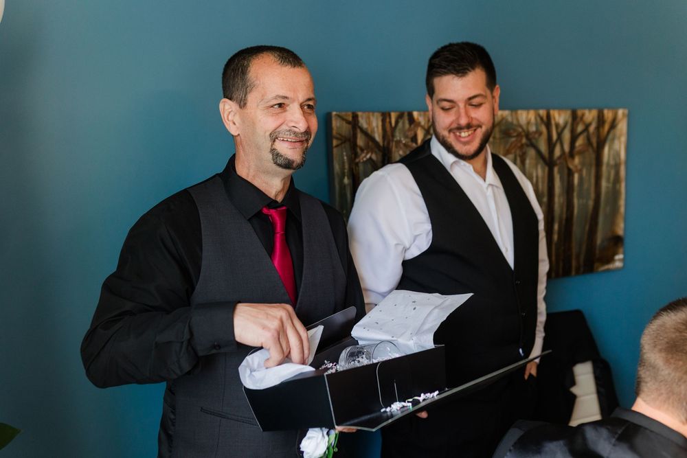 A group of people in formal attire share a laugh while seated at a table during an event.