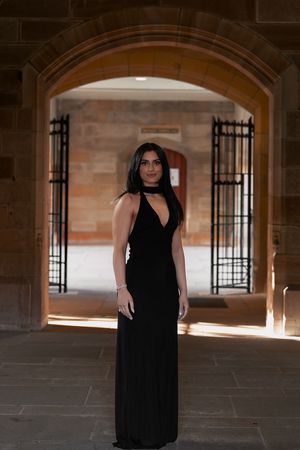 Artistic portrait through arched church hallway with dramatic natural lighting and shadows.