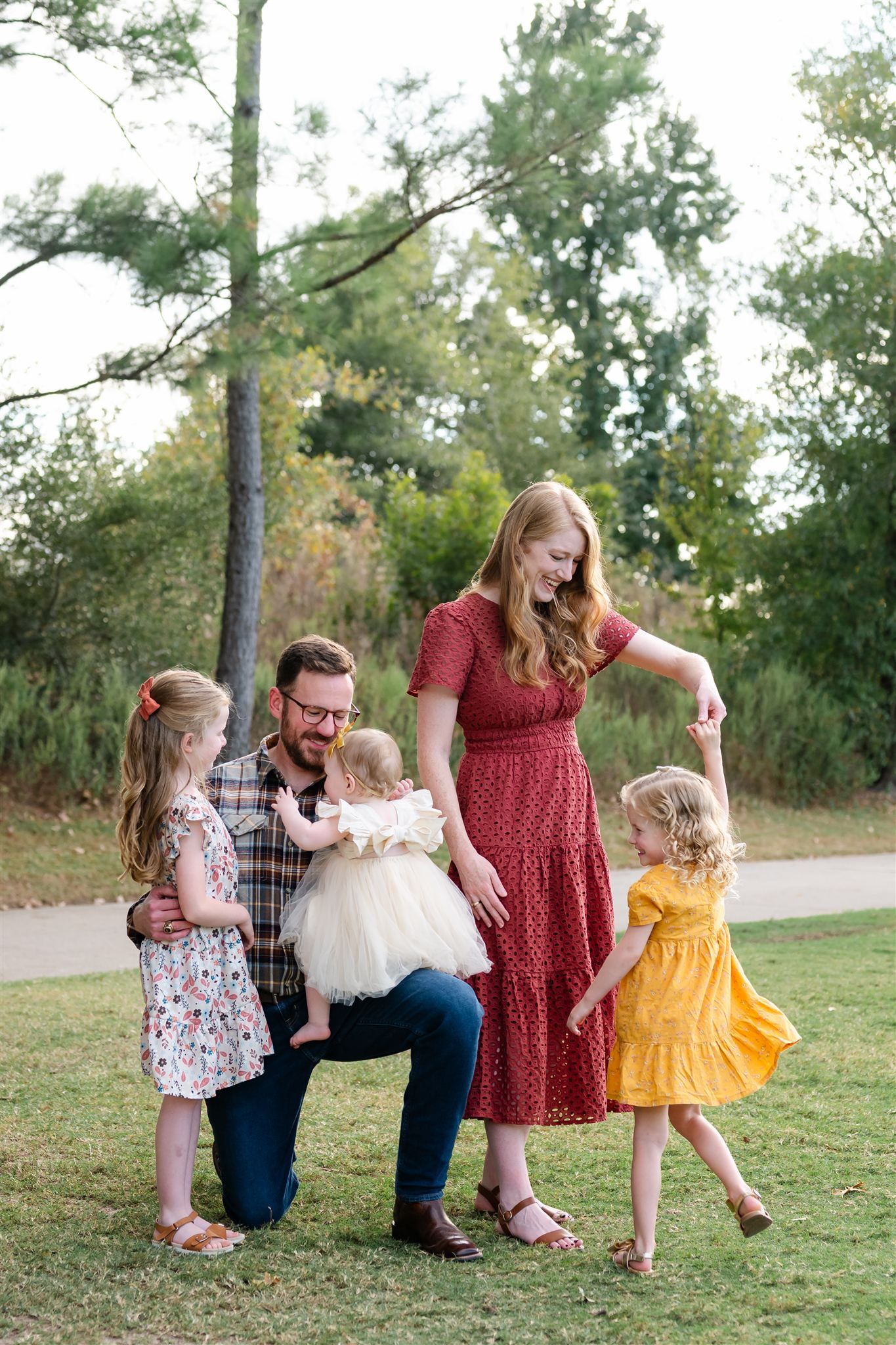 A family in coordinating outfits enjoys playful moments together on a grassy hill during an outdoor photo session.