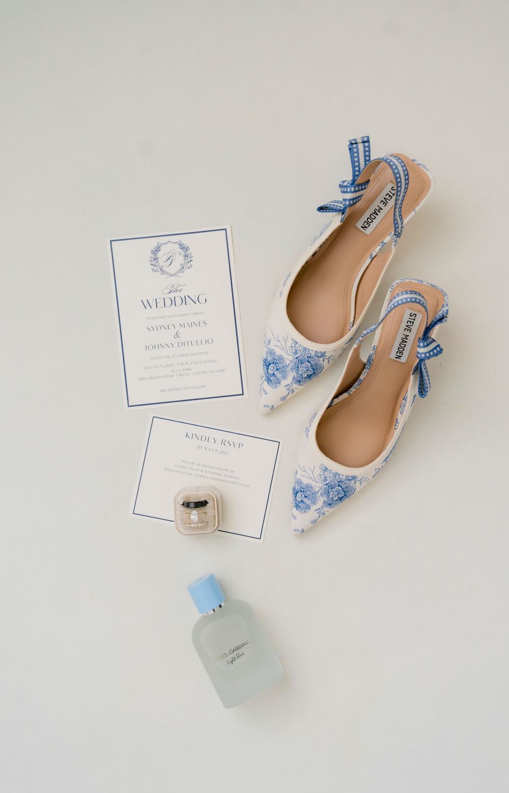 Elegant wedding invitation suite with blue details and bridal shoes on white background.