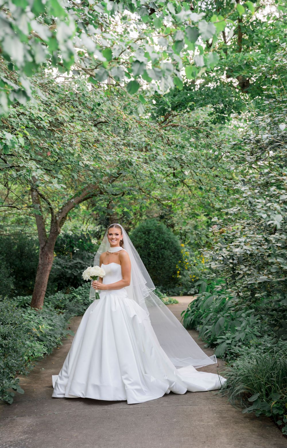 A beautiful garden path lined with blooming trees and lush greenery creates a romantic outdoor setting.