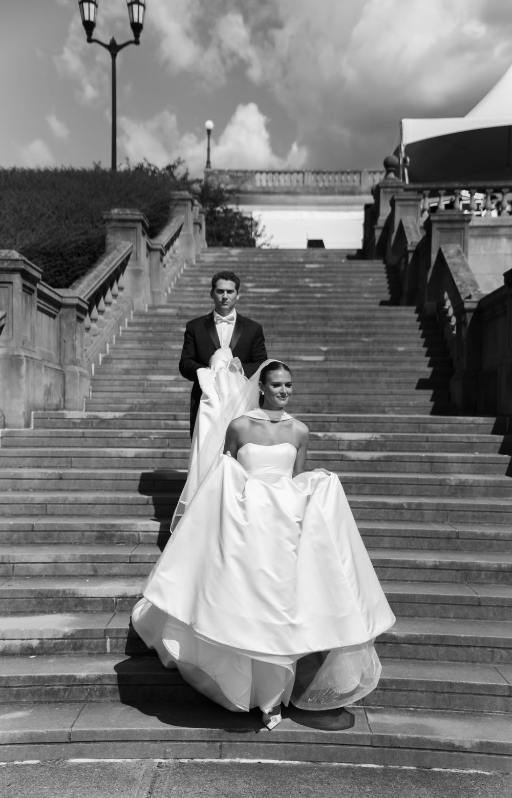 A sequence of black and white photographs showing a bride in a white gown descending stone steps outdoors.