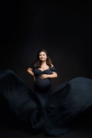 Dramatic fashion portrait series in black dress with flowing fabric against dark background.