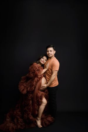 Artistic portrait series showing a couple in intimate poses against dark background wearing orange and burgundy ruffled dress.