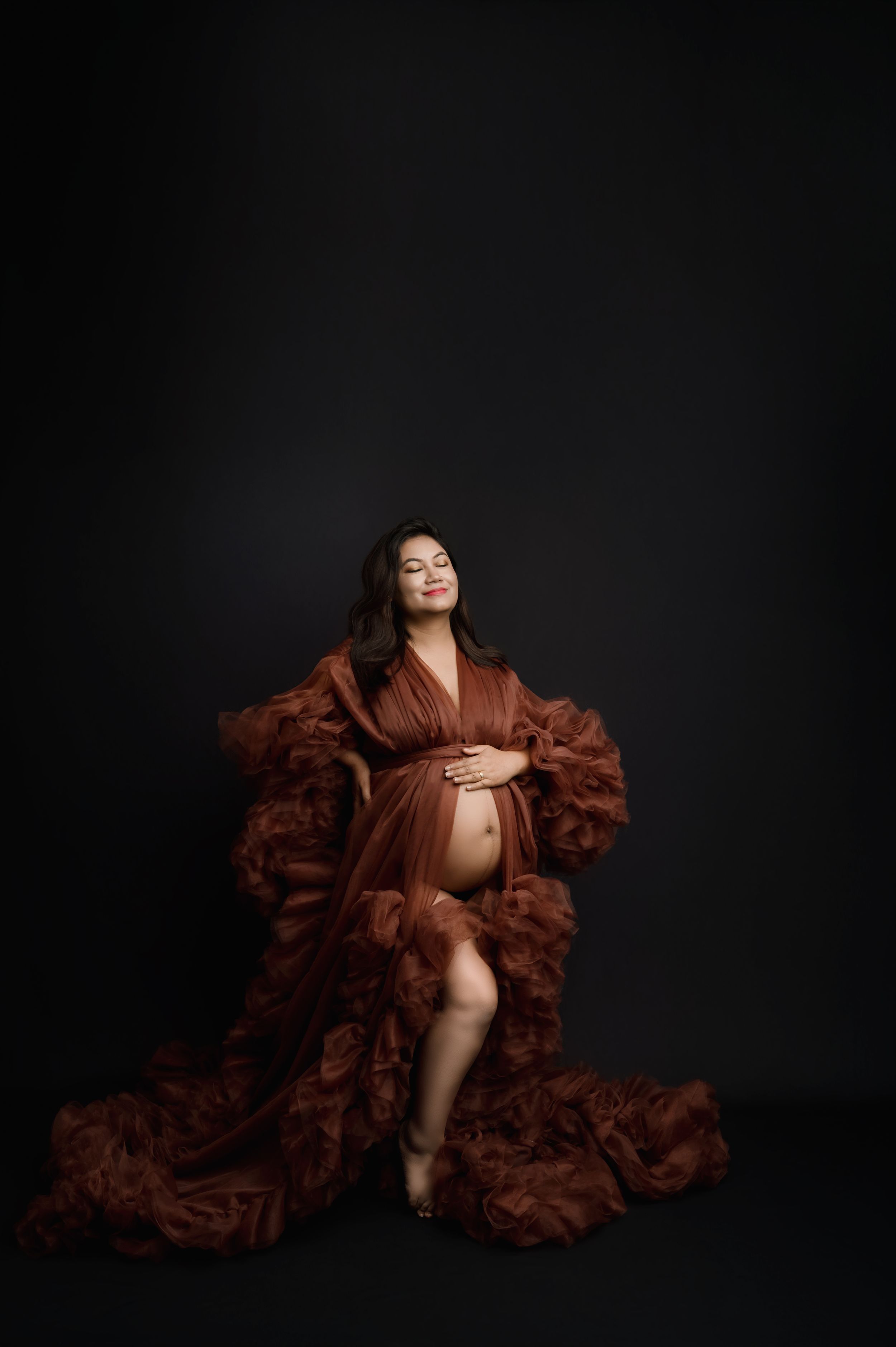 A dramatic boudoir photo series featuring a brown ruffled robe against a dark background.