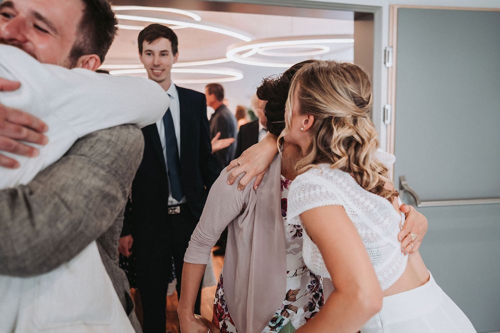 Wedding guests embrace and share emotional moments during a celebration in an indoor venue.