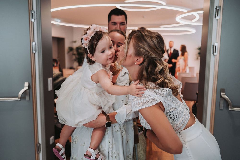 A tender moment captured during a wedding celebration in a modern venue with circular lighting fixtures.