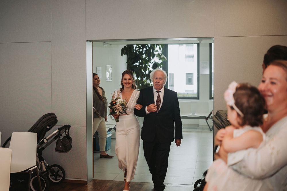 Wedding guests gather in an elegant indoor venue with modern decor and glass doors.