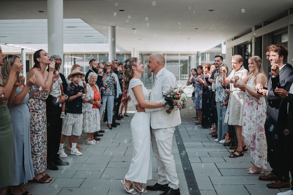 Wedding guests line the walkway outside as newlyweds celebrate their first kiss as a married couple.