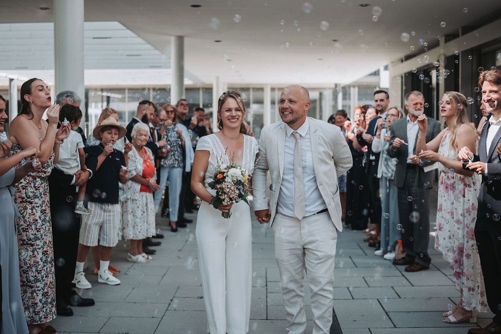 Wedding guests line up along a covered walkway to celebrate the newlyweds during their reception exit.