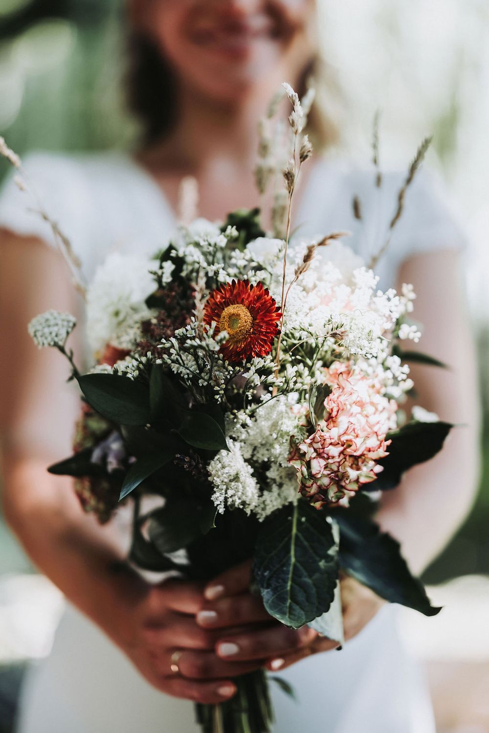 Close-up of romantic bouquet featuring white, pink and burgundy flowers with dark green foliage.