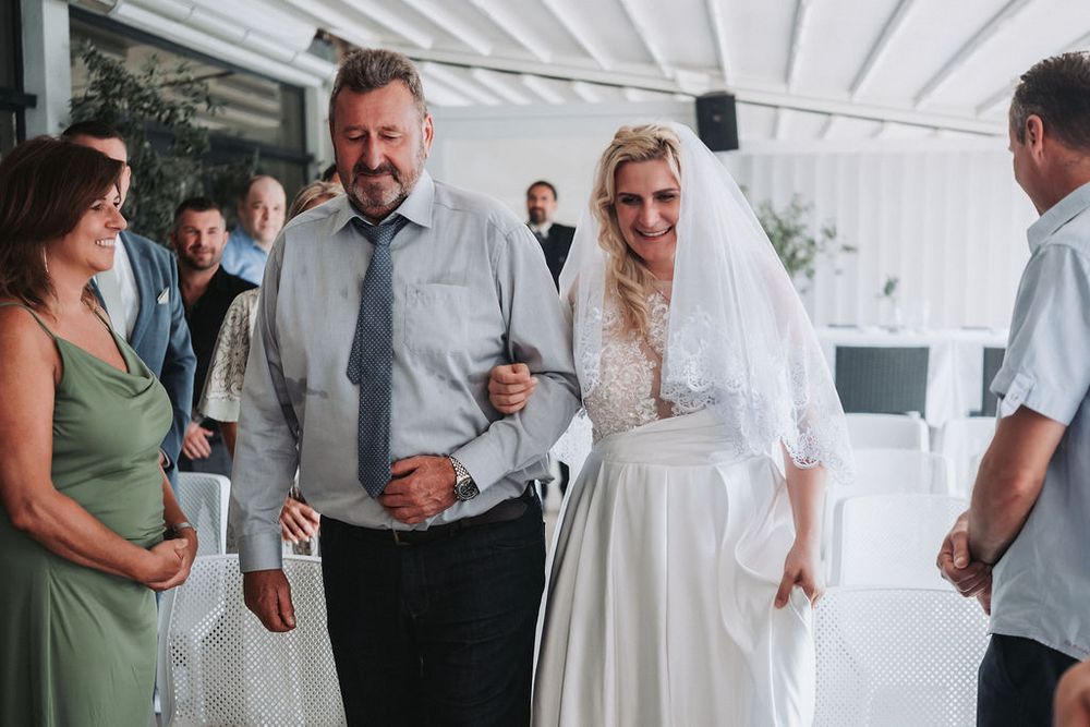 A group of wedding guests socializing and mingling under a white tent during a celebration.