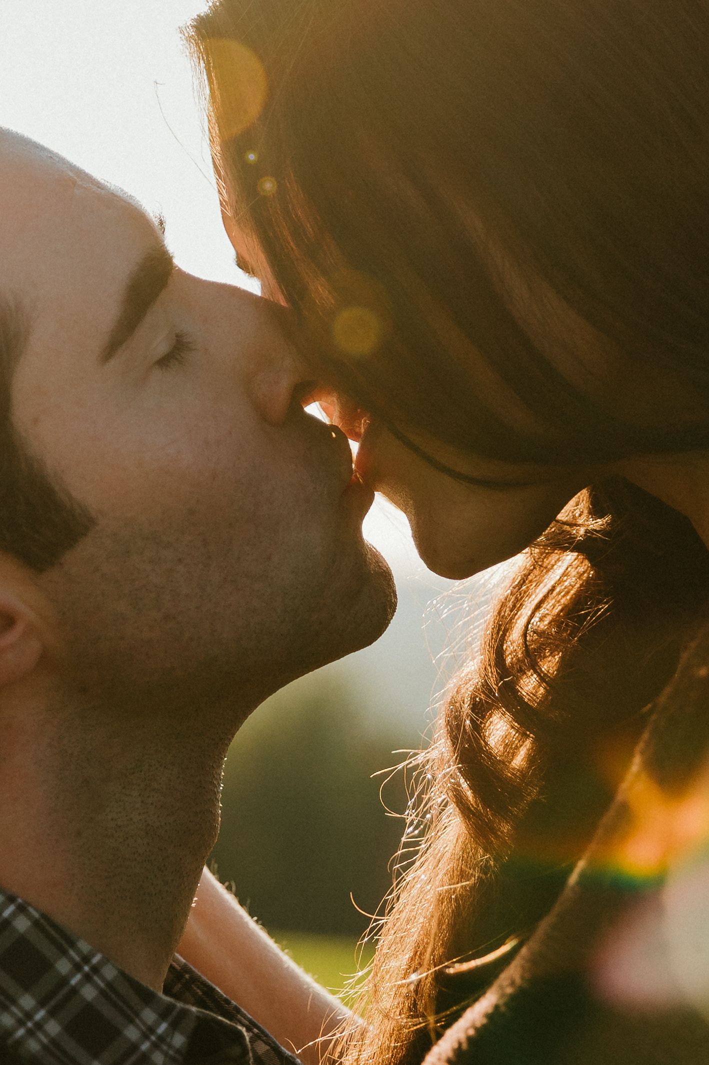 A silhouetted couple sharing an intimate moment in golden sunlight during sunset.