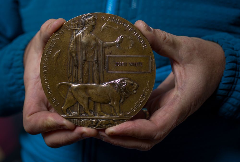 Hands holding and displaying different angles of a large bronze or brass military service medallion or plaque.