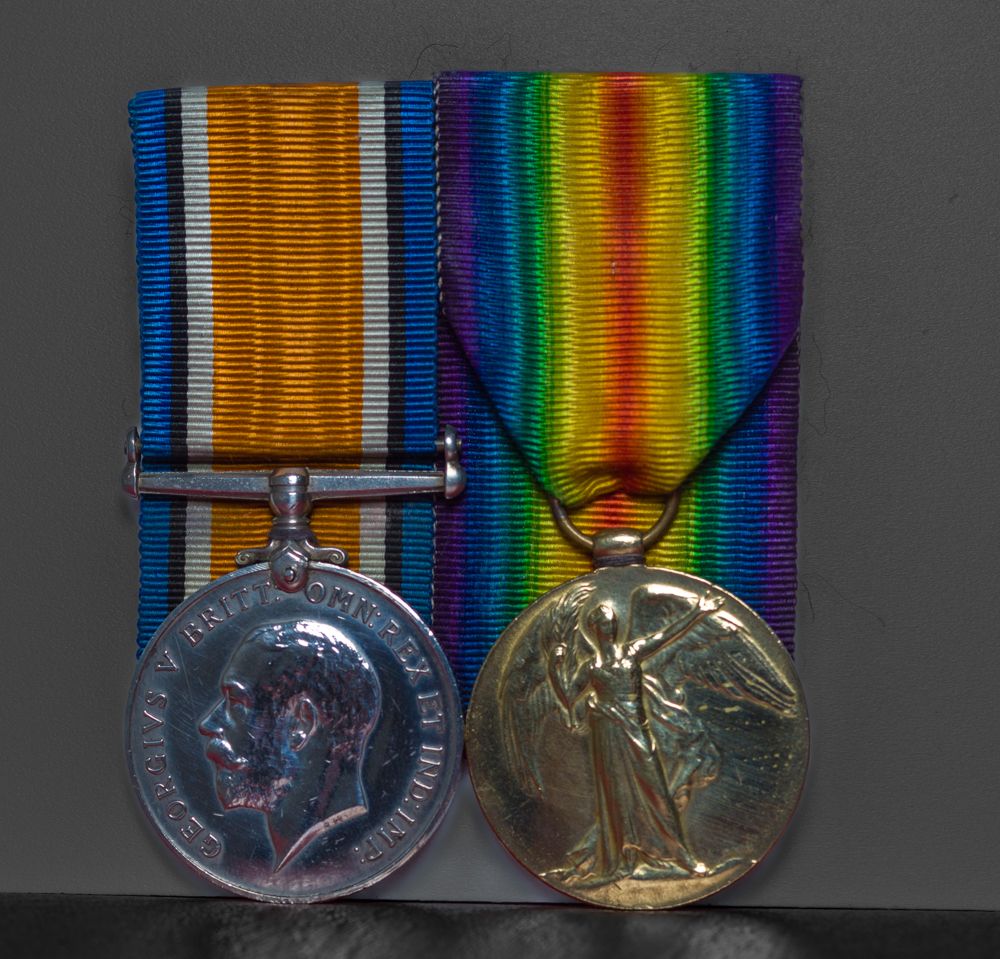 A set of British World War I military service medals with striped ribbons displayed on a dark background.