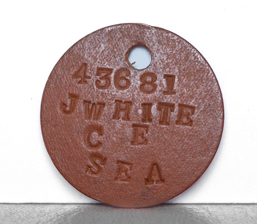 Four vintage clay identification tags with numbers and text engraved on their reddish-brown surfaces.