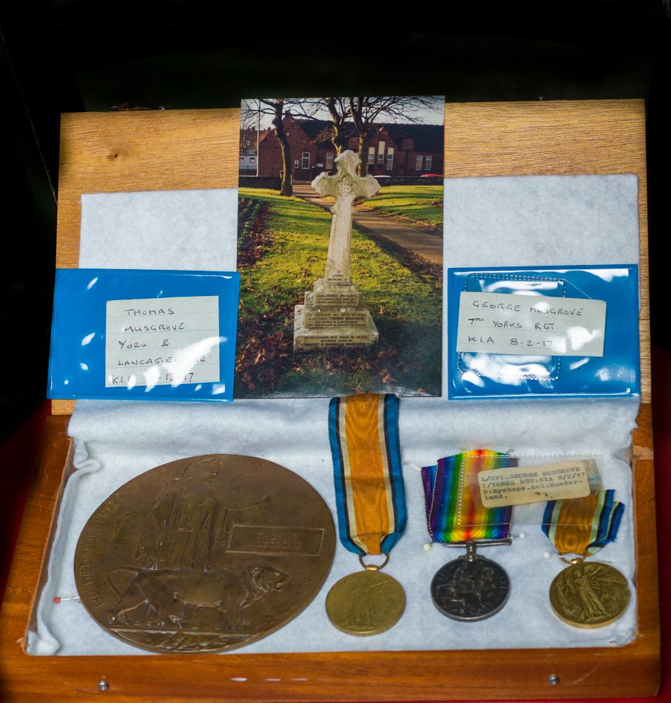 Military medals and commemorative plaques displayed on a wooden surface.