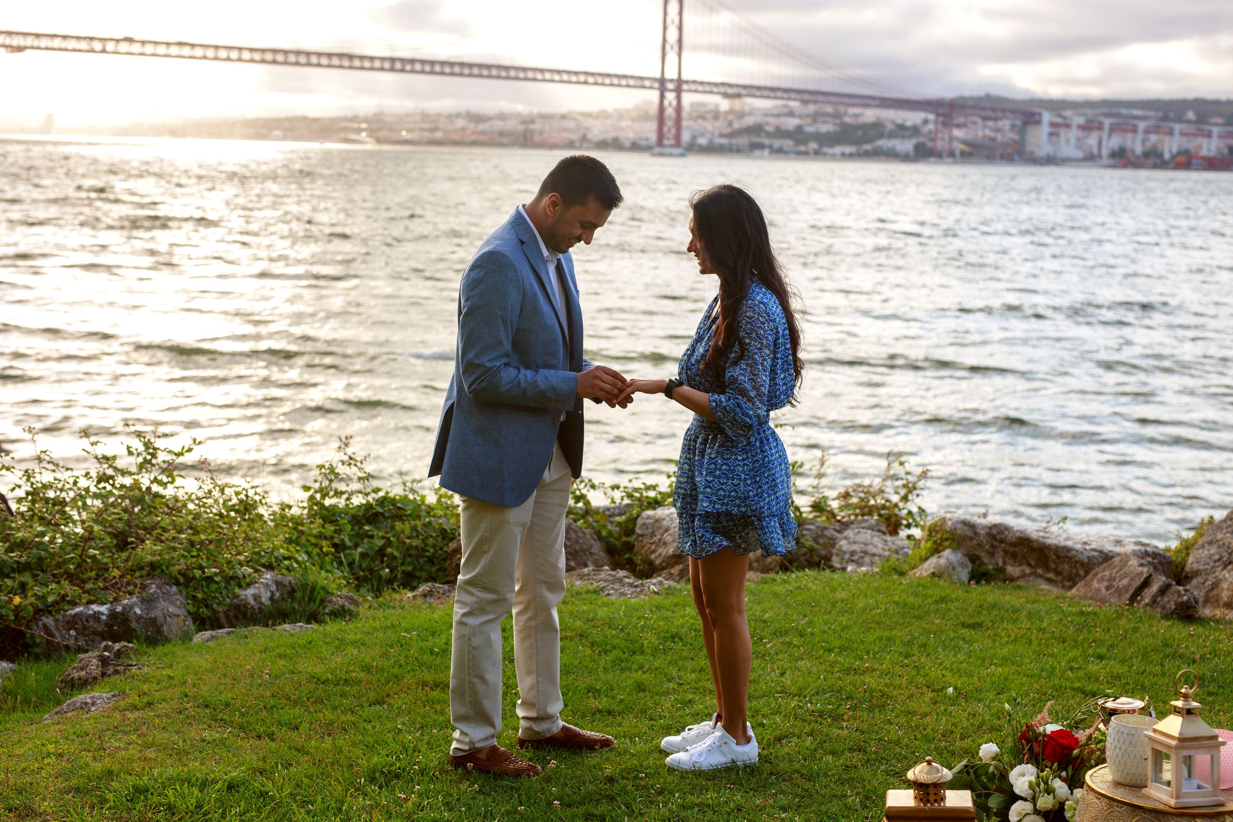 A romantic proposal scene on a grassy cliff overlooking the San Francisco Bay at sunset.