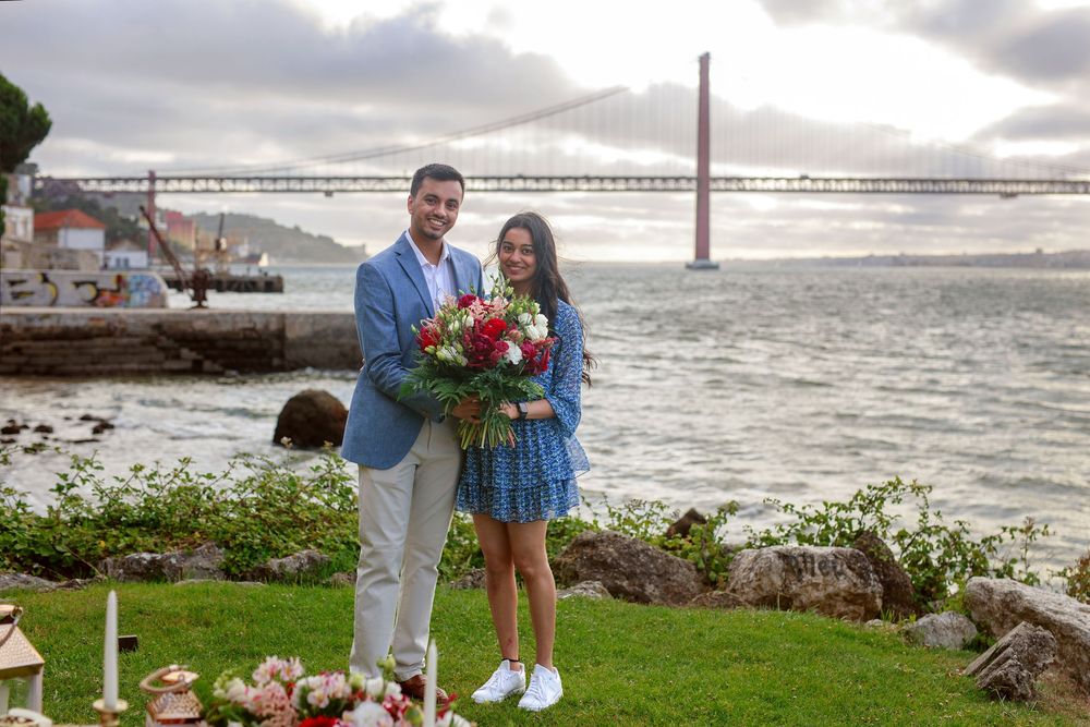 A couple shares a romantic moment on a misty beach with the Golden Gate Bridge visible in the background.