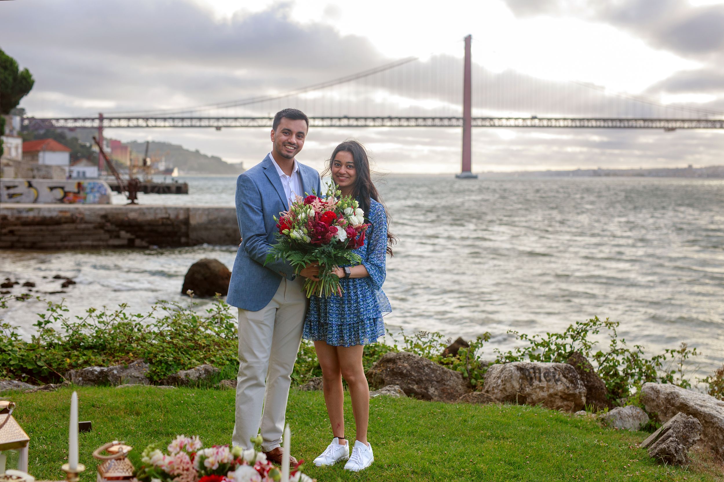 A couple shares a romantic moment on a misty beach with the Golden Gate Bridge visible in the background.