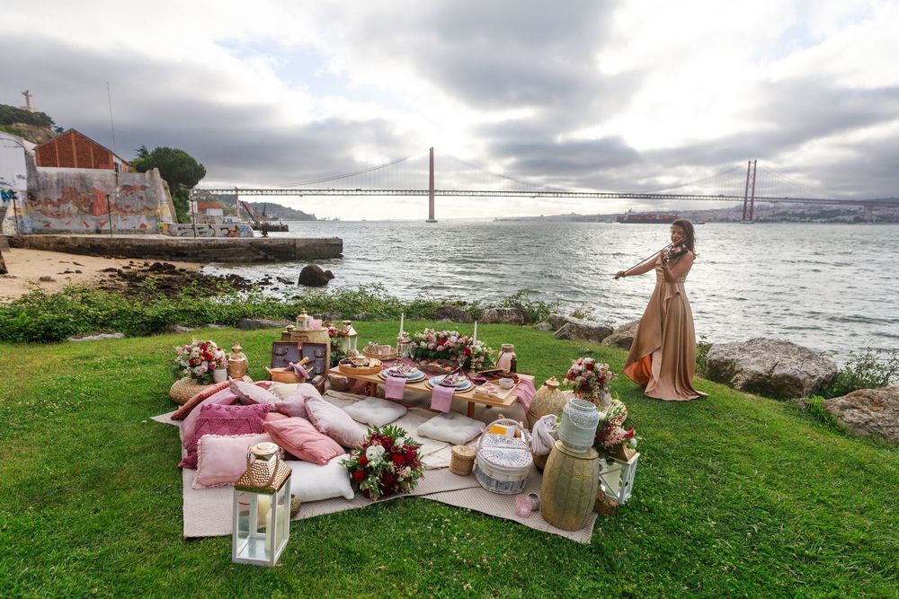 A picturesque seaside picnic setup with blankets and pillows overlooking the Golden Gate Bridge.