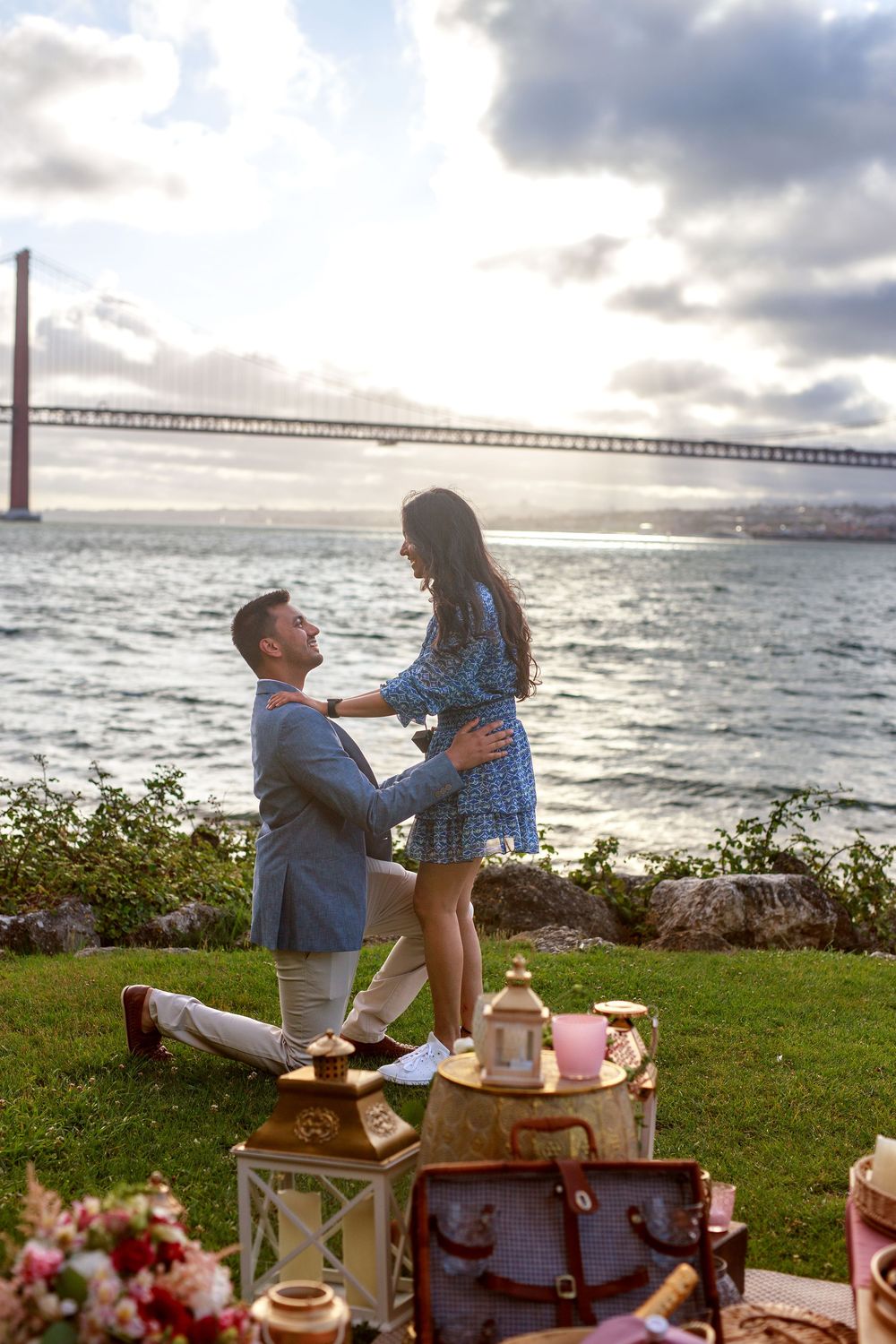 A romantic proposal setup with vintage decor and lanterns overlooking the bay at sunset.