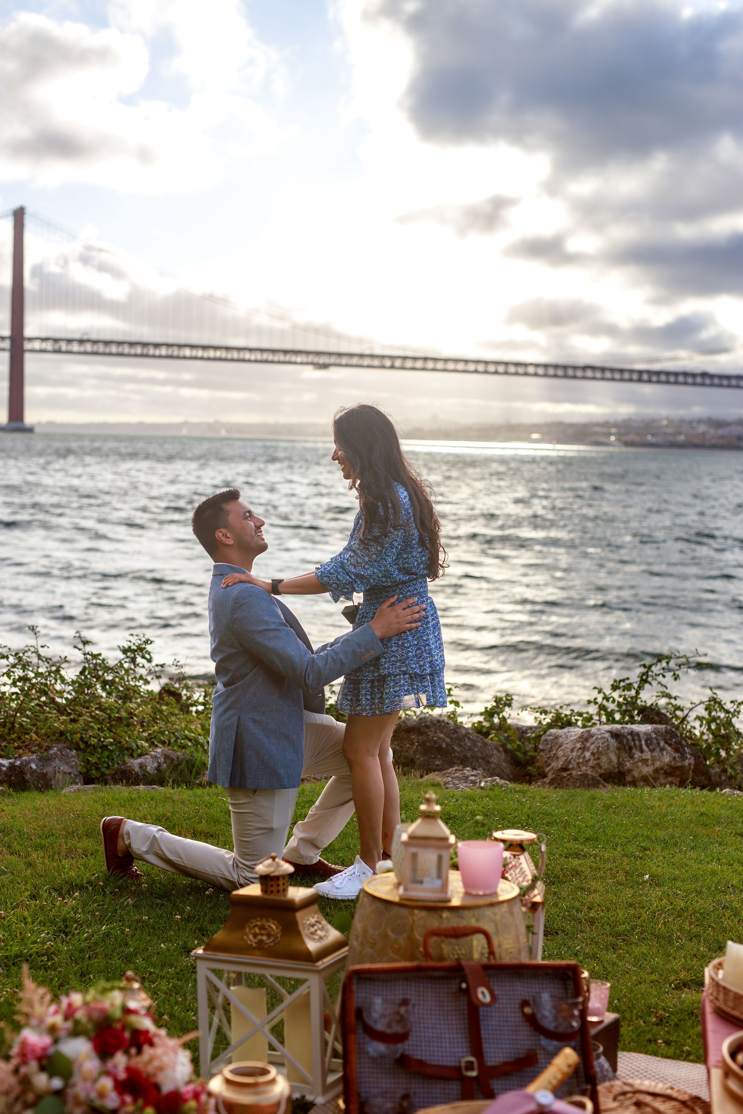 A romantic proposal setup with vintage decor and lanterns overlooking the bay at sunset.