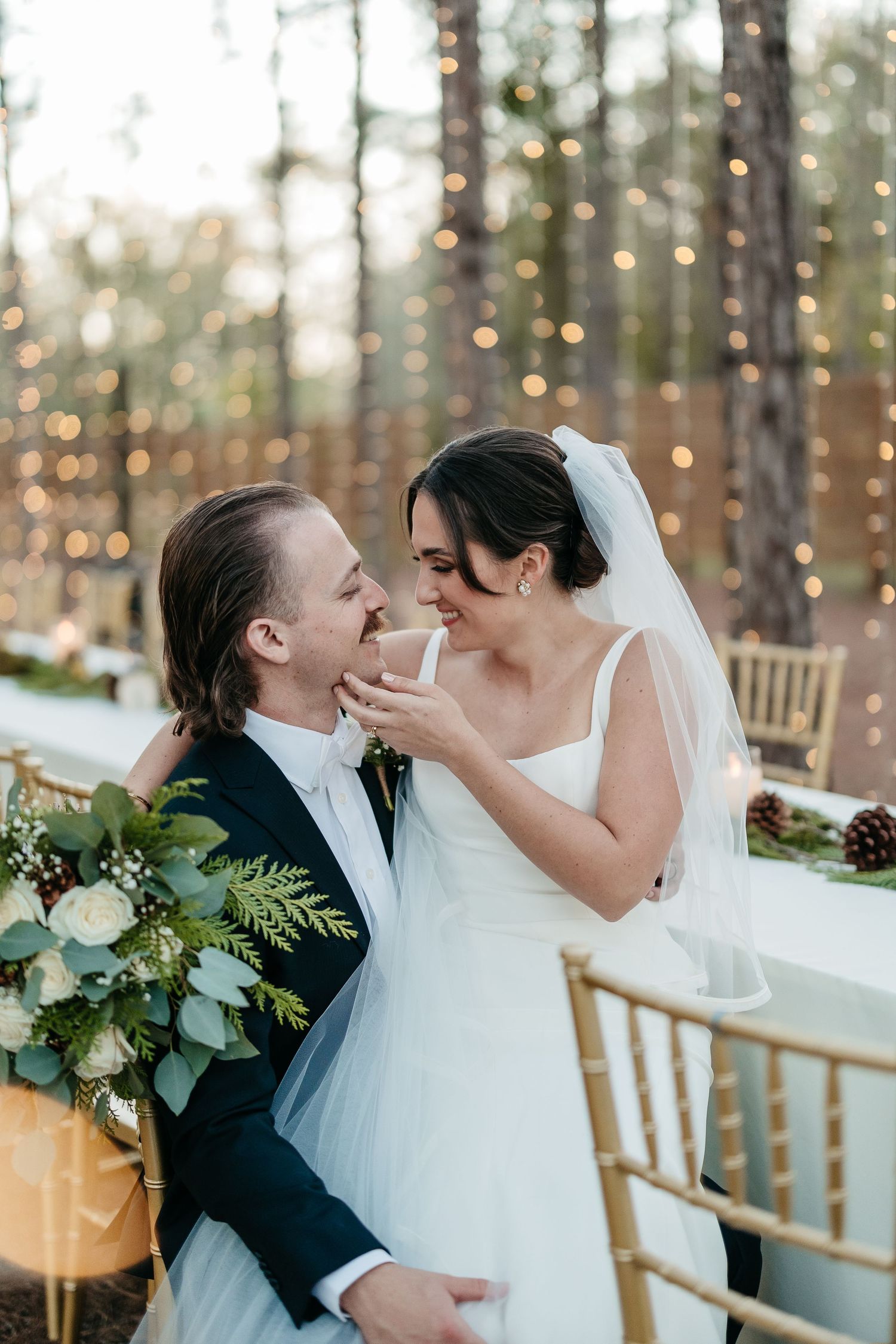 Romantic wedding portraits with twinkle lights and pine trees creating a magical forest atmosphere.