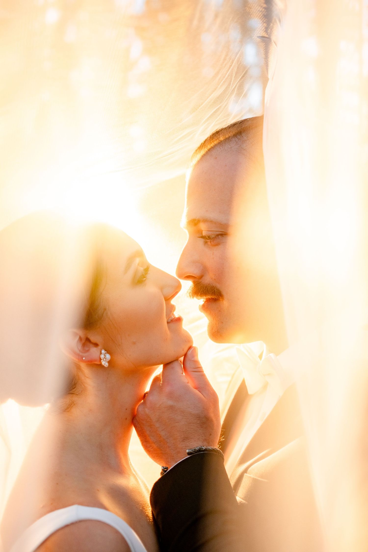 Ethereal close-up wedding portraits bathed in warm sunset light and flowing fabric.