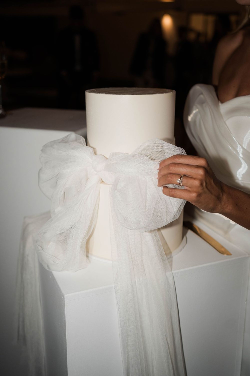 Close-up sequence showing a white organza bow being tied and adjusted on a wedding dress.