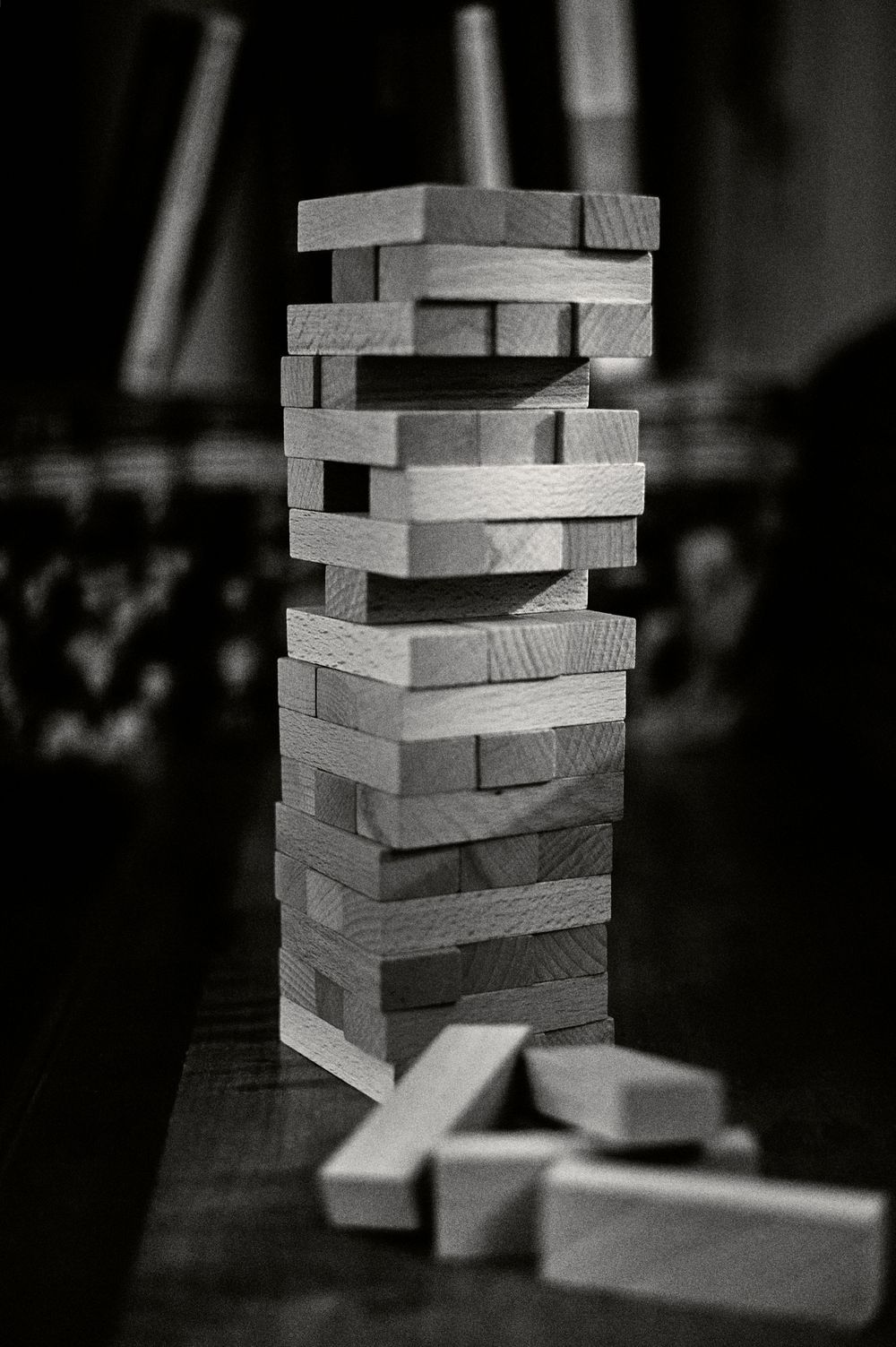 Black and white close-up photos show wooden Jenga blocks stacked in increasingly precarious arrangements.