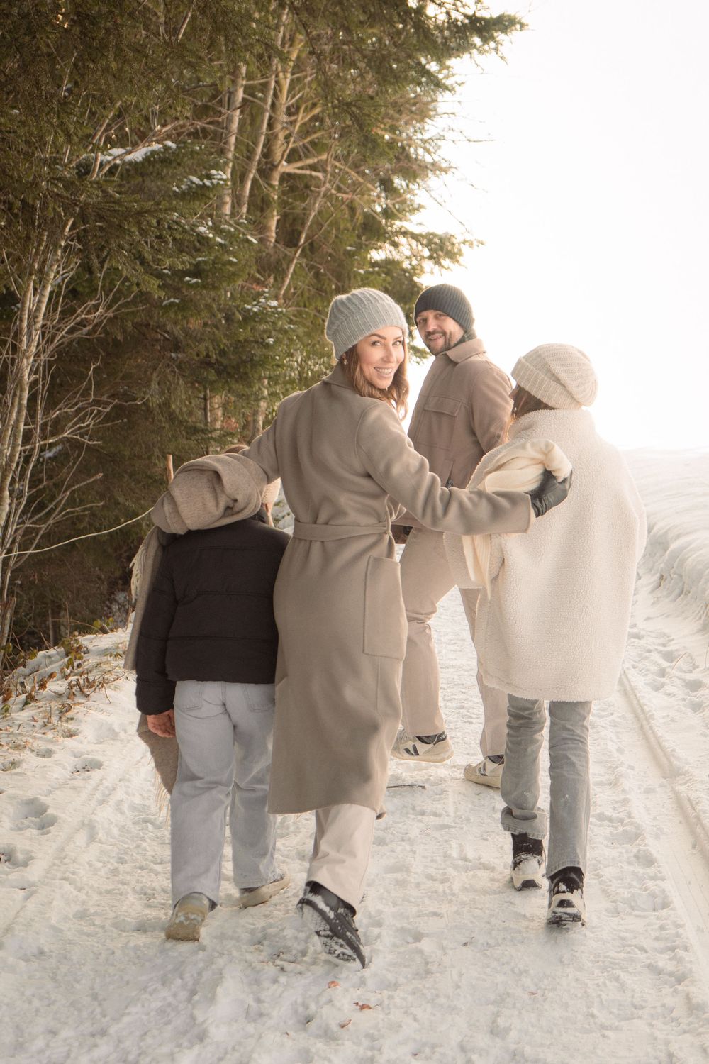 Friends walking arm in arm along a snowy winter trail.