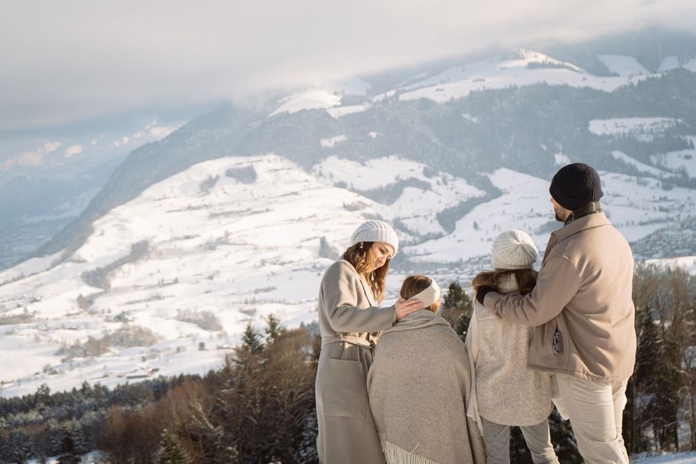 People admiring a scenic mountain view on a snowy winter day.