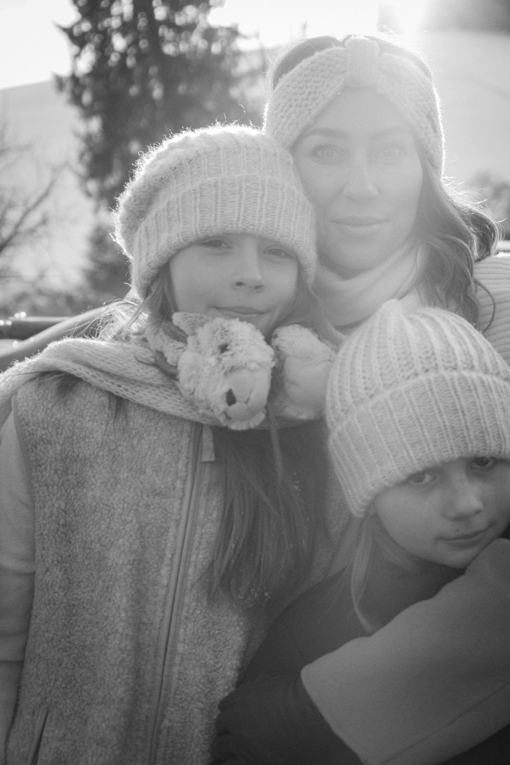 A winter portrait of people wearing knit hats in the snow.
