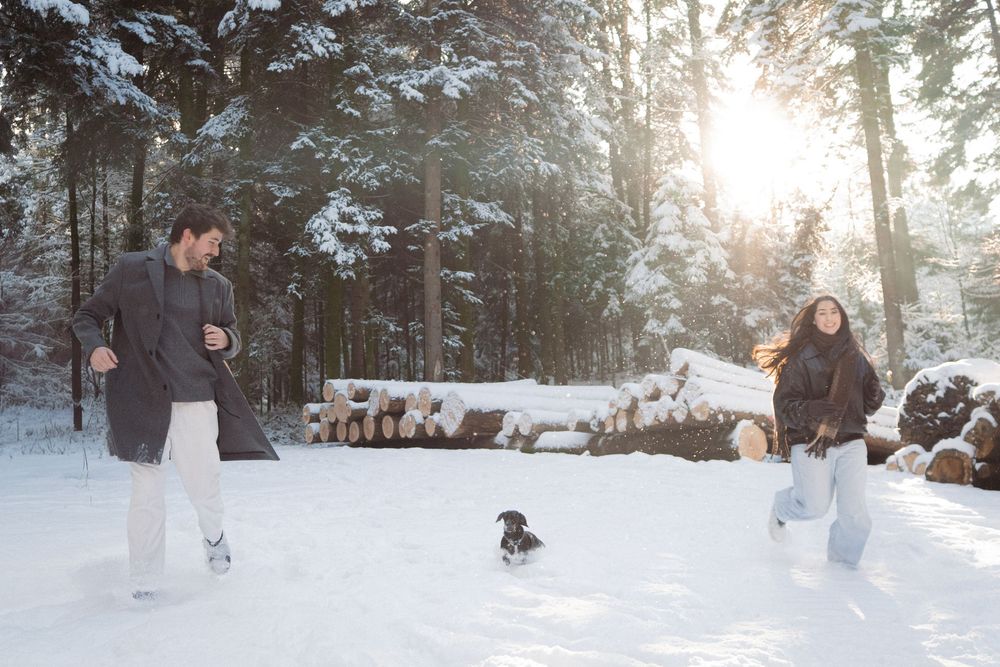 Snow-covered forest path with winter adventurers and dog walking together.
