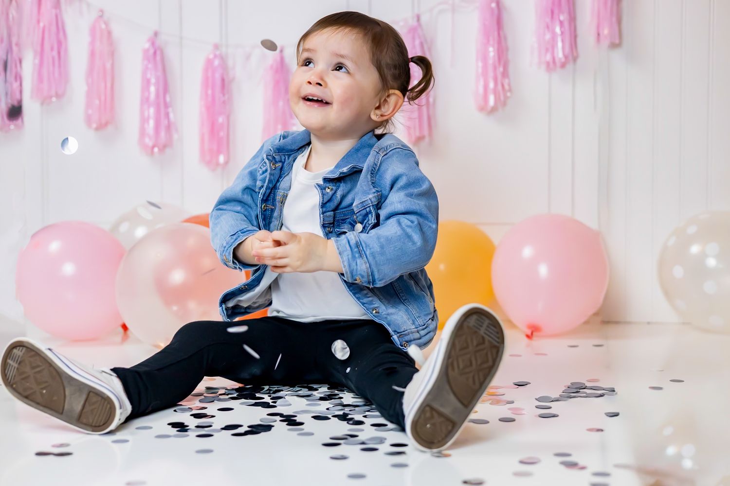 A baby in a yellow onesie crawls and looks upward on a white background.