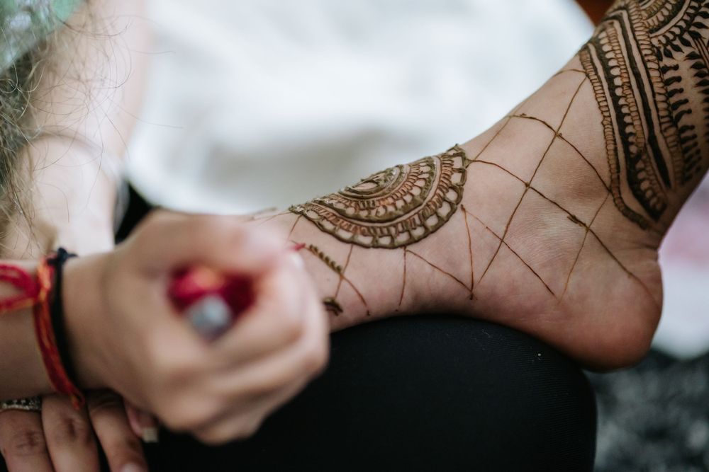 Close-up view of intricate henna mehndi design being applied to foot with traditional patterns and details.