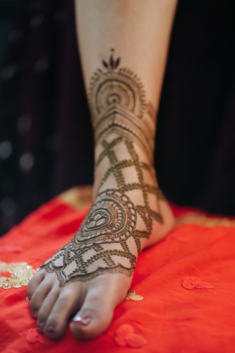 Intricate henna design adorns a foot resting on vibrant red fabric, showcasing traditional mehndi artistry.